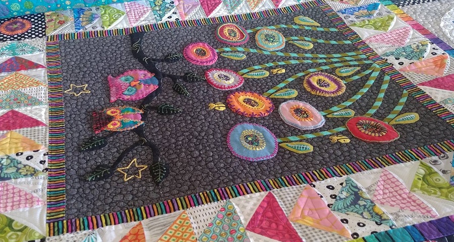 brightly colored applique owl quilt with densely quilted pebbles