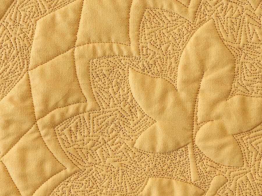 golden yellow wholecloth quilt with leaf stitching surrounded by stipple