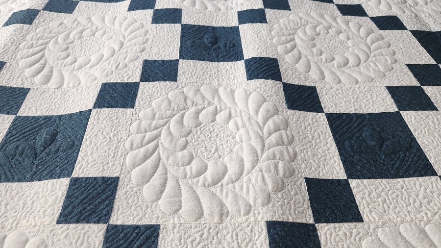 two-toned single Irish chain blue and white quilt stitched with feather wreaths and dense background quilting