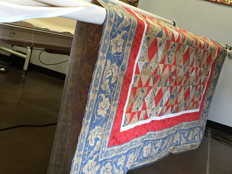 Quilt top draped over rails before quilting