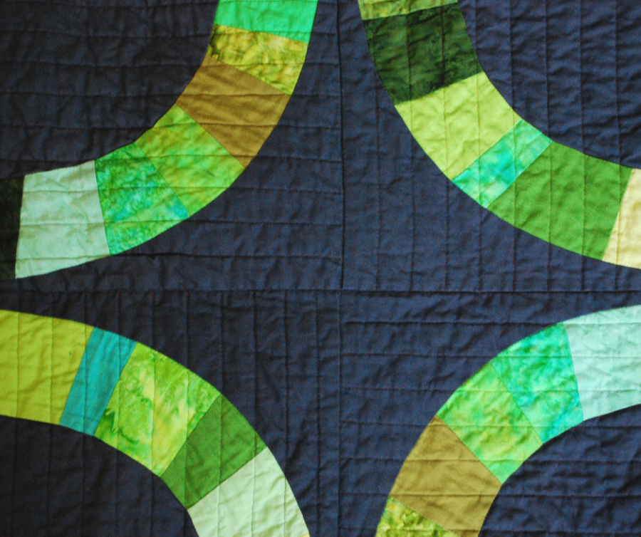 Bold pieced quilt in green and black with line quilting